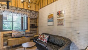 A cozy cabin interior with a wooden ceiling, a leather sofa, a small table, and a TV. - Kantapää d2 by Interhome (Sodankylä)