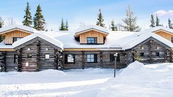 A log cabin hotel with multiple wooden buildings, snow-covered roofs, and a clear sky.