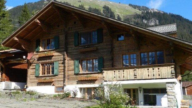A wooden chalet with a balcony, a garage, and a mountain backdrop. - Bijou Arnensee by Interhome (Feutersoey)