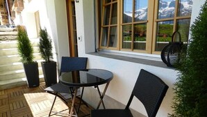 A small outdoor seating area with two chairs and a table, a window with a view of mountains, and potted plants. - Bijou Arnensee by Interhome (Feutersoey)