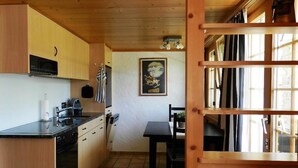 A compact kitchen with wooden cabinets, a black countertop, and a tiled floor. - Bijou Arnensee by Interhome (Feutersoey)
