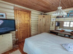 L’intérieur d’une cabine avec une porte en bois, un téléviseur, un lit et une bibliothèque.