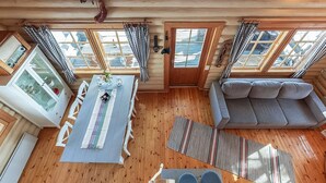 Eine Hütte mit Essbereich, einer Couch und einem großen Fenster.