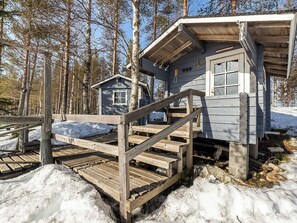 Une cabane en bois avec un petit porche et un escalier menant à une porte.