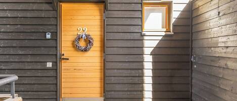 A wooden door with a wreath, a small window, and a metal step leading to the entrance.
