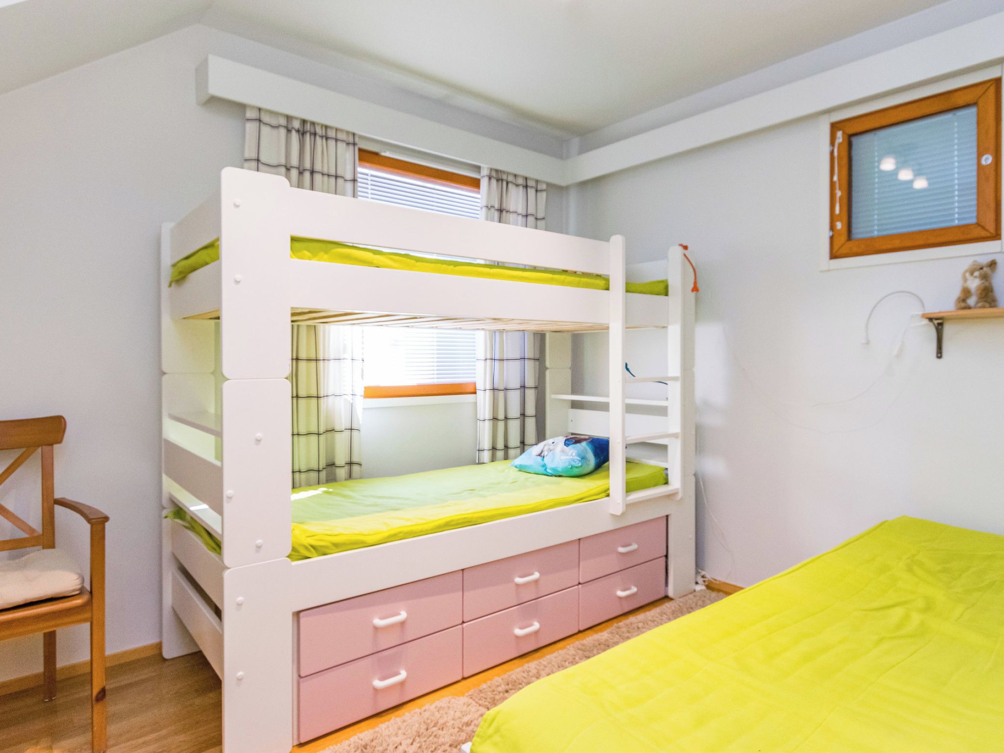Un lit superposé avec un bureau et des tiroirs, une chaise et un lit recouvert d’une couverture jaune.