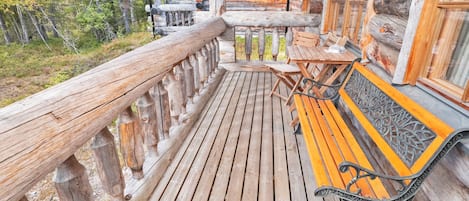 A wooden deck with a bench and table, surrounded by a wooden railing.