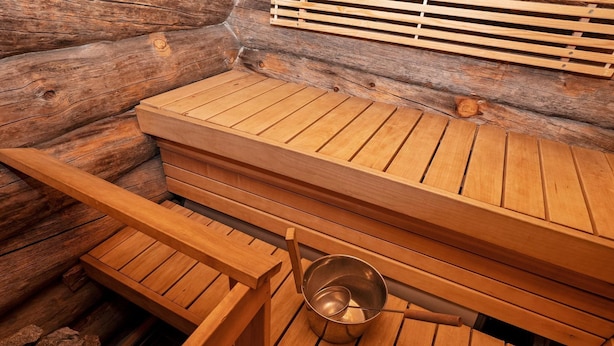 Una sauna con bancos de madera y un recipiente metálico.