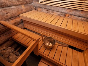 Un sauna avec des bancs en bois et un récipient en métal.