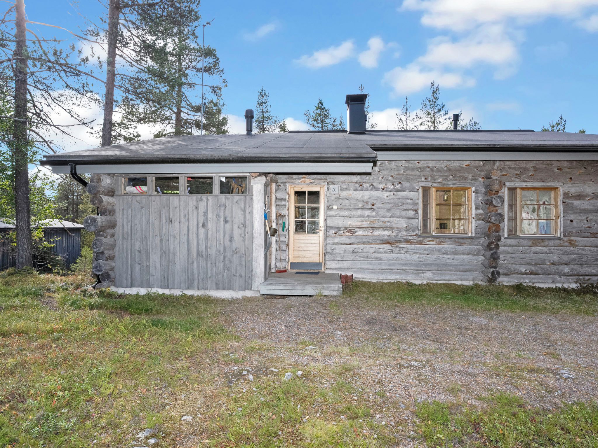 A log cabin with a wooden door, a small porch, and a chimney.