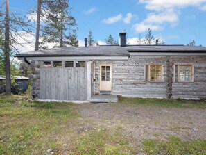 A log cabin with a wooden door, a small porch, and a chimney.