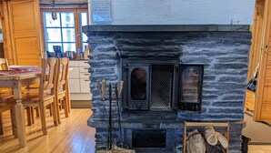 Un interior rústico con chimenea de piedra, muebles de madera y un comedor.