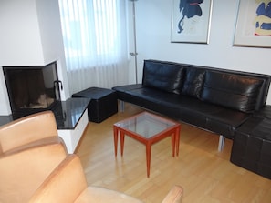 A modern living room with a black leather sofa, a glass coffee table, and a brown leather armchair. - Dorfstrasse 15 Appartement/Fewo 7-Bettwohnung by Interhome (Engelberg)