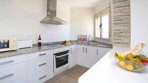 A modern kitchen with white cabinetry, a stainless steel range hood, a built-in oven, a microwave, and a fruit bowl on the counter. - Apartment Primun by Interhome (Calpe/Calp)