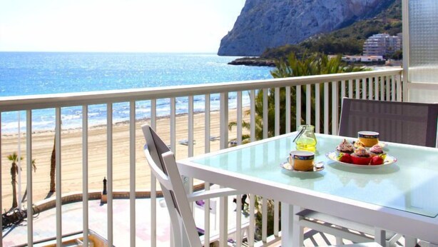 A balcony with a glass table, chairs, and a view of the sea and a mountain. - Apartment Primun by Interhome (Calpe/Calp)