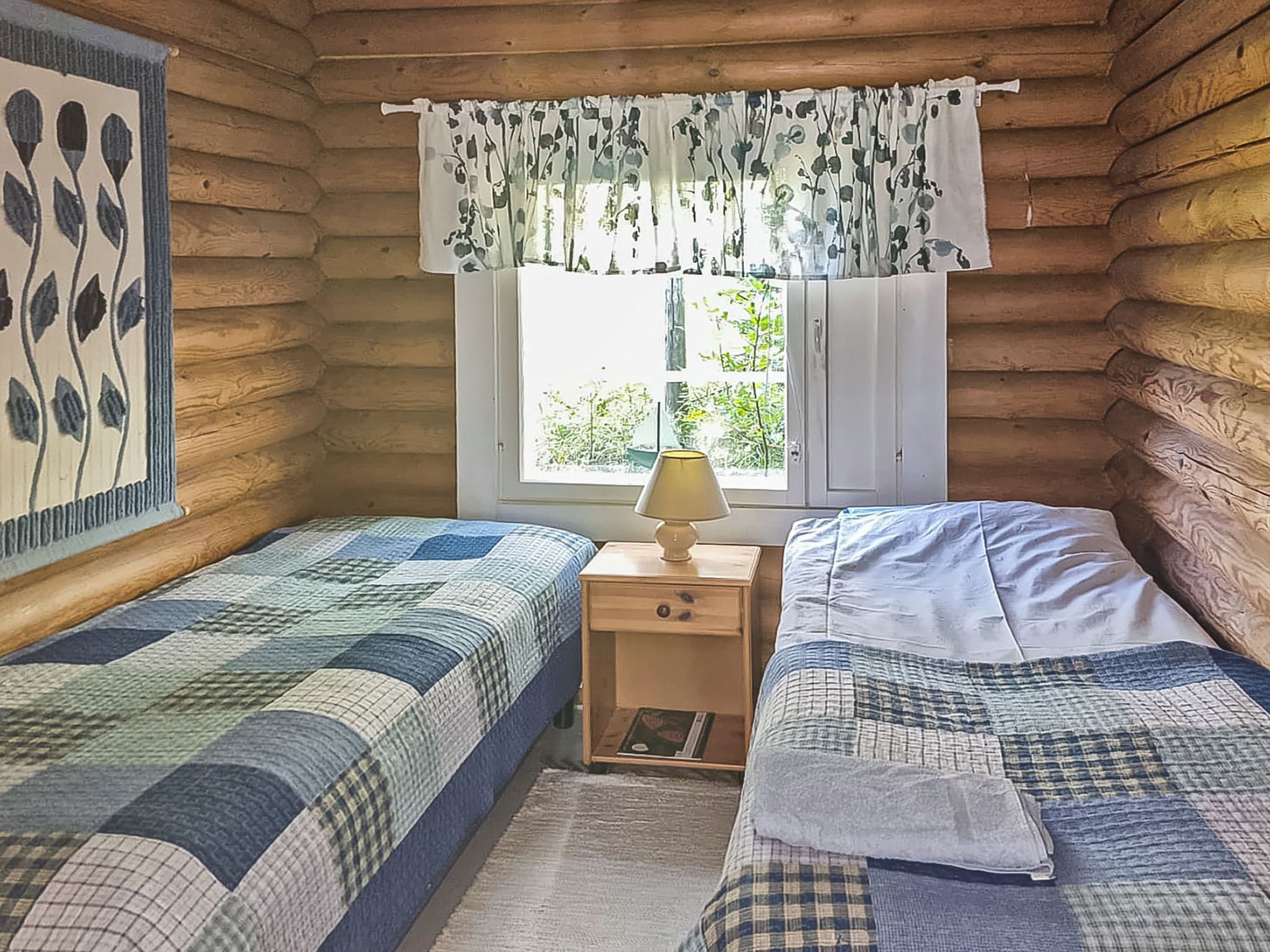 Une cabine comprenant deux lits, une fenêtre avec vue et une table de chevet avec une lampe.