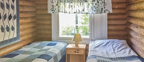 Une cabine comprenant deux lits, une fenêtre avec vue et une table de chevet avec une lampe.