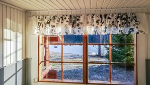 A room with a large window, wooden shutters, and a ceiling fan.