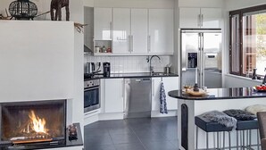 A modern kitchen with white cabinets, a central island, a built-in oven, and a fireplace. - Villa ylläs 203 by Interhome (Ylläsjärvi)