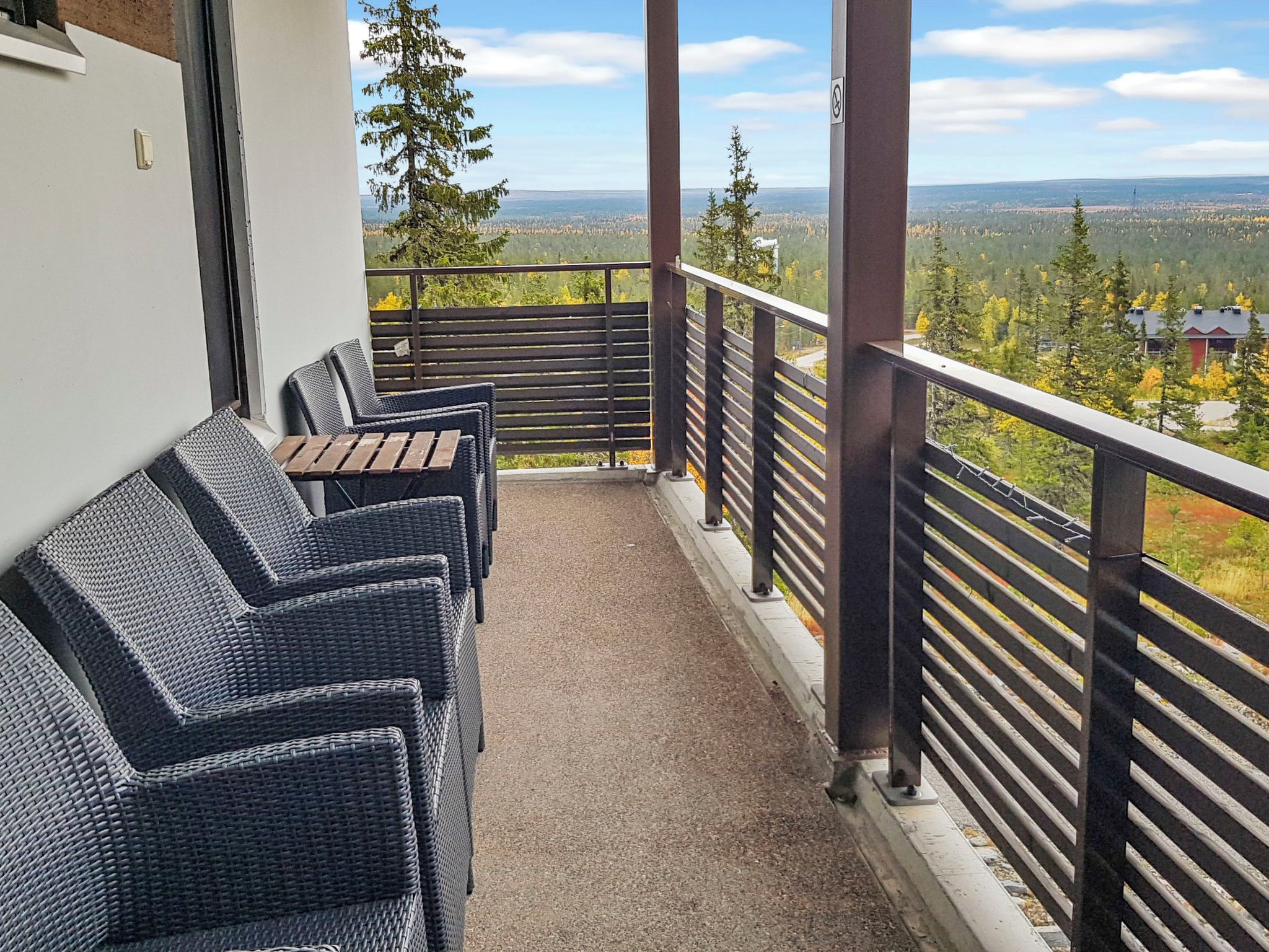 A balcony with wicker furniture and a view of a forested landscape.