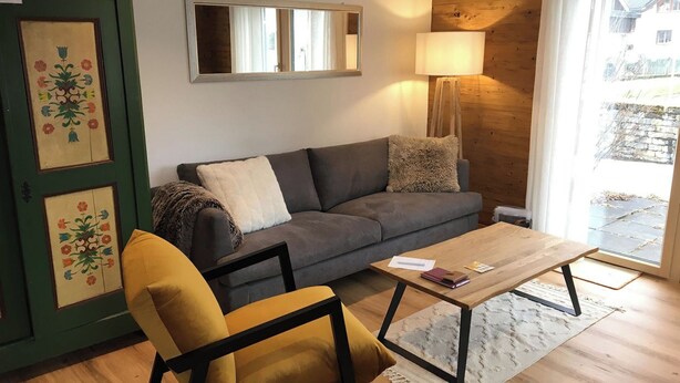 Un salon comprenant un canapé, un fauteuil, une table basse et une porte ornée de motifs floraux.