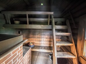 Interior de madera con una pared de ladrillo, una escalera de madera y una pequeña mesa con un cuenco de fruta.