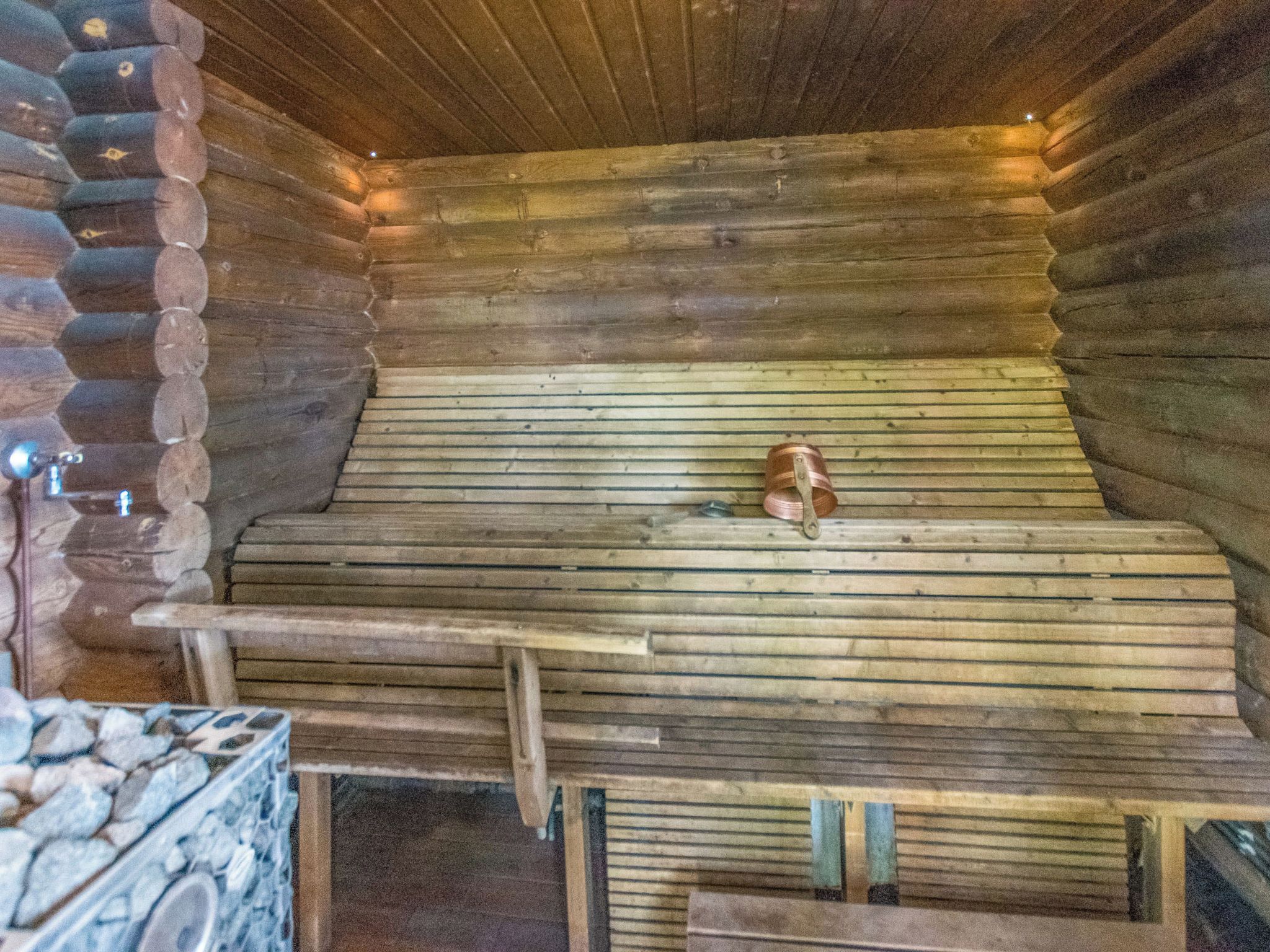 A log cabin interior with a wooden bench and a dog lying on it.