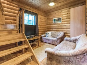 A log cabin interior with a wooden staircase, a sofa, and a television. - Elimäki by Interhome (Pöytyä)