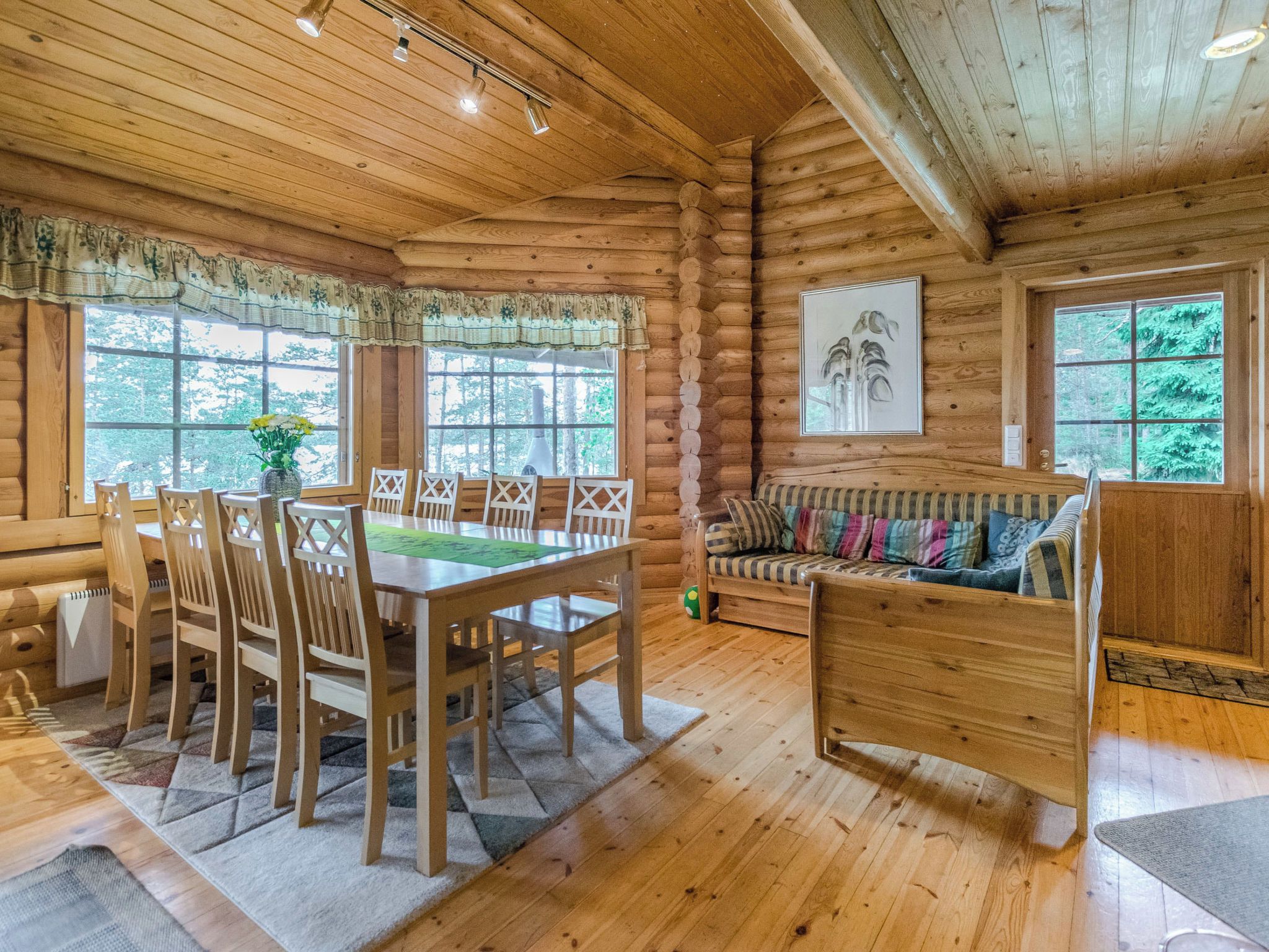 L’intérieur d’une cabane en rondins comprend un coin repas, un canapé et un tableau accroché au mur.