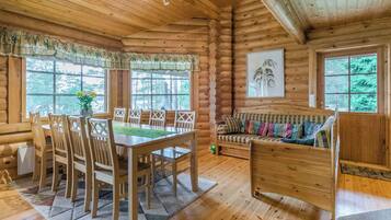 L’intérieur d’une cabane en rondins comprend un coin repas, un canapé et un tableau accroché au mur.