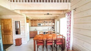 Une cuisine spacieuse avec des meubles en bois, un coin repas comprenant une table et des chaises, et une grande fenêtre agrémentée de rideaux.