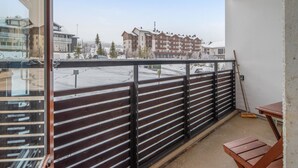Un balcon donnant sur un quartier résidentiel, avec des immeubles à plusieurs étages et un parking.
