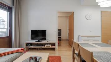 En moderne stue med fjernsyn, spisebord med stole, sofa og et lille bord med bakke.