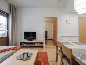 Een moderne woonkamer met een flatscreen televisie, een eettafel met stoelen, een bank en een klein tafeltje met dienblad.