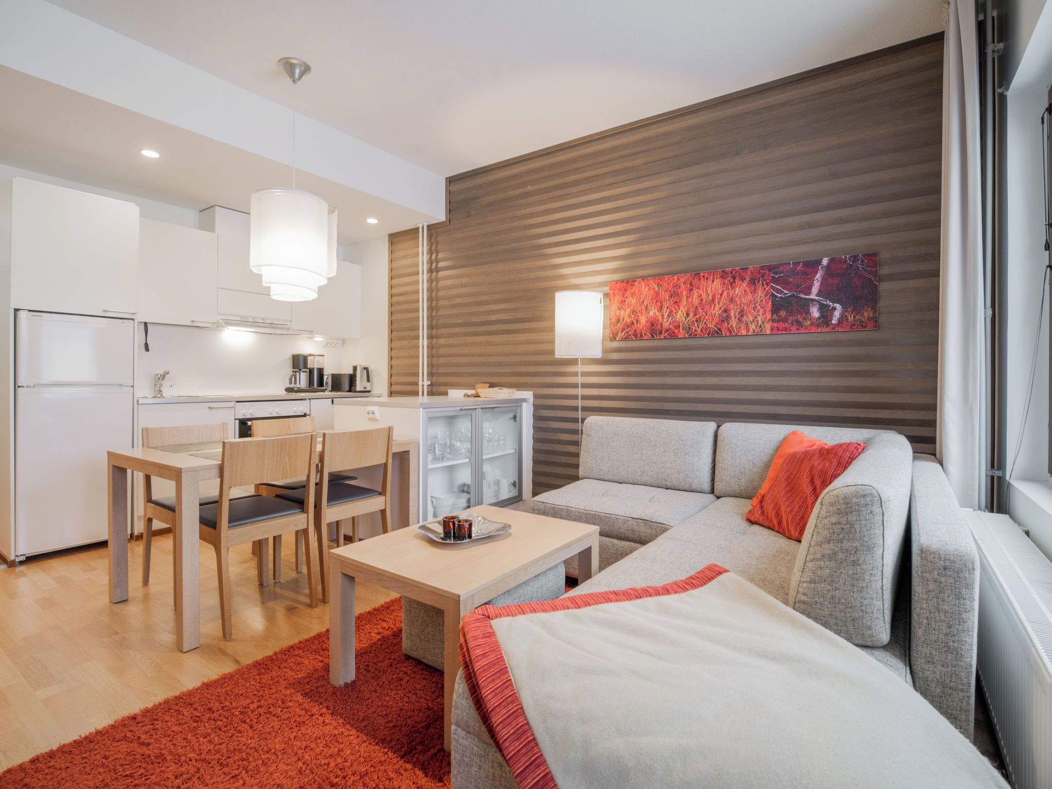 En moderne stue med sofa, sofabord og et spiseområde med stole og bord.