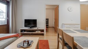 Une pièce moderne et bien éclairée, dotée d’un téléviseur à écran plat, d’une table à manger et d’un coin salon confortable.