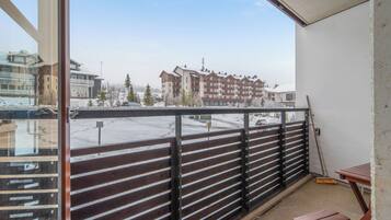 En balkon med udsigt over et boligområde, et træbord og en kost.