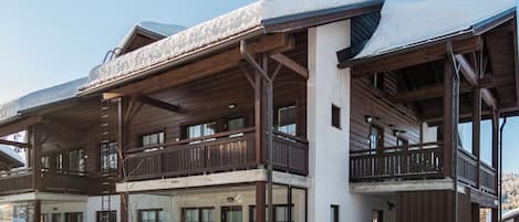 Un immeuble en bois à plusieurs étages, doté de balcons et de grandes fenêtres, entouré de neige.