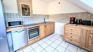 Cocina compacta con microondas, horno, lavabo y armarios de madera.