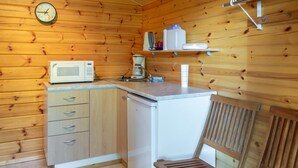 Una cucina compatta con pareti in legno, un forno a microonde, una macchina da caffè e un piccolo frigorifero.