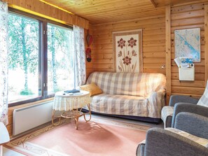 A cozy cabin interior with a checkered sofa, a wicker table, and a map on the wall. - Pikkupuro by Interhome (Nilsiä)