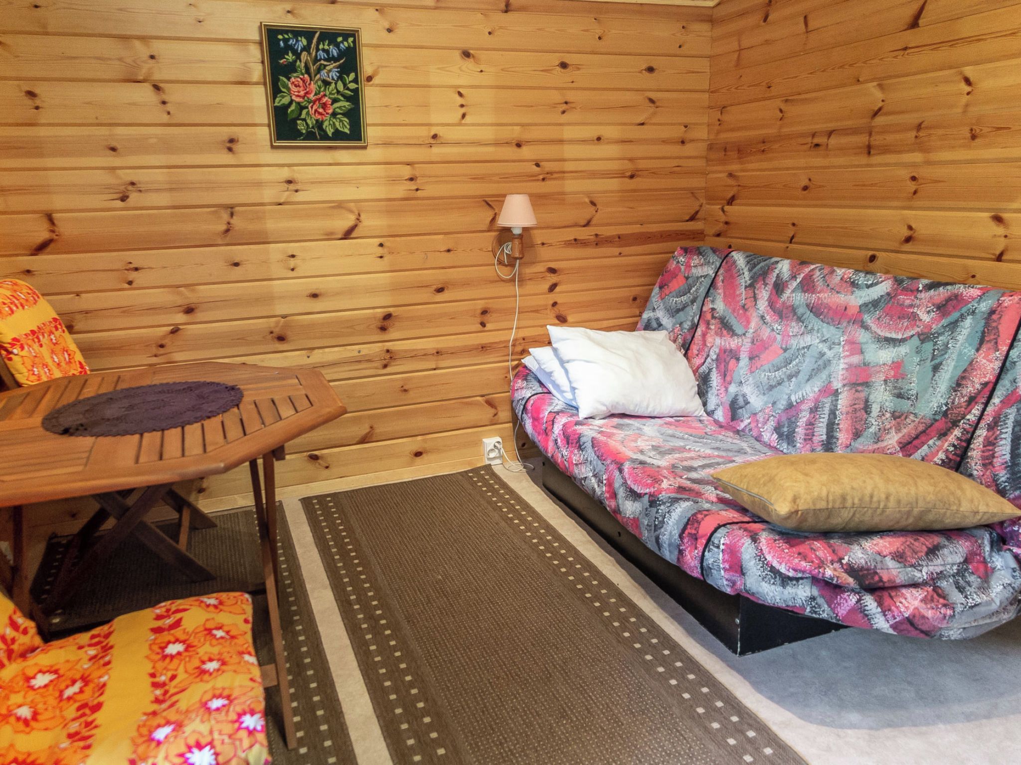 L'intérieur d'un chalet en bois, avec un canapé, une table et une lampe.