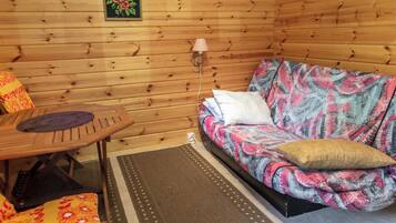 L'intérieur d'un chalet en bois, avec un canapé, une table et une lampe.