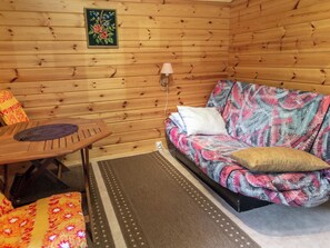 A wooden cabin interior with a sofa, a table, and a lamp. - Pikkupuro by Interhome (Nilsiä)