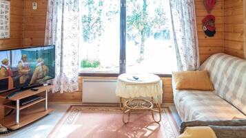 L'intérieur d'un chalet confortable, avec un téléviseur, un canapé et une petite table.