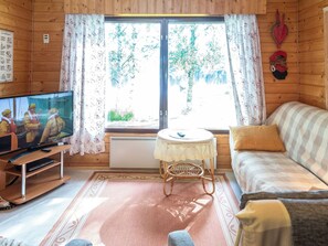 A cozy cabin interior with a television, sofa, and a small table. - Pikkupuro by Interhome (Nilsiä)