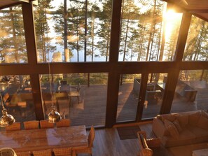 Un interior espacioso con amplias ventanas que dan a una terraza y un bosque.