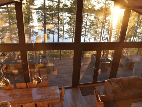A spacious interior with large windows overlooking a deck and forest.