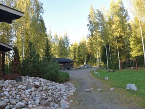 A gravel path leading to a wooden cabin surrounded by a forest.