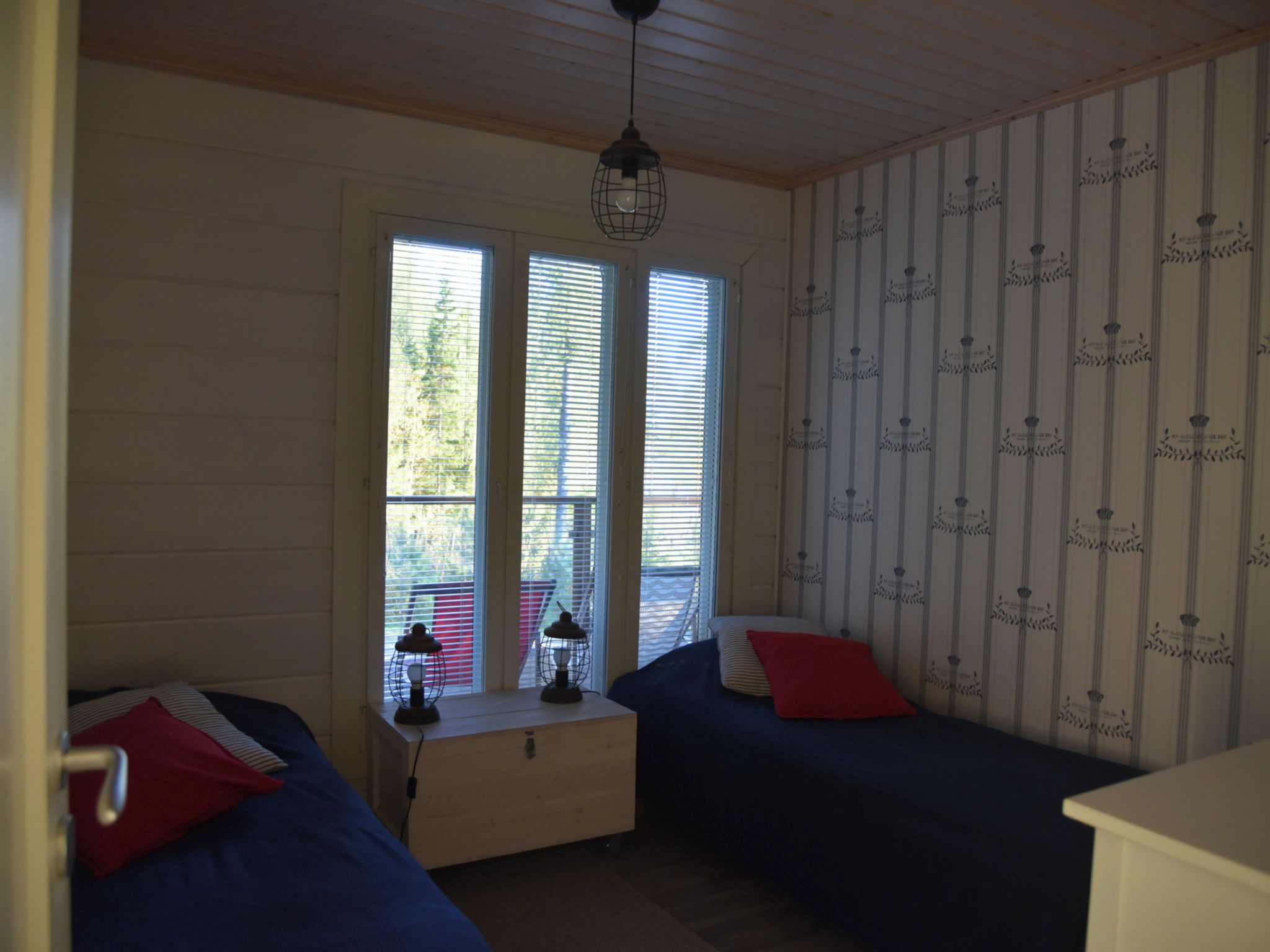 Una habitación con dos camas, una mesita de noche y una ventana con persianas.